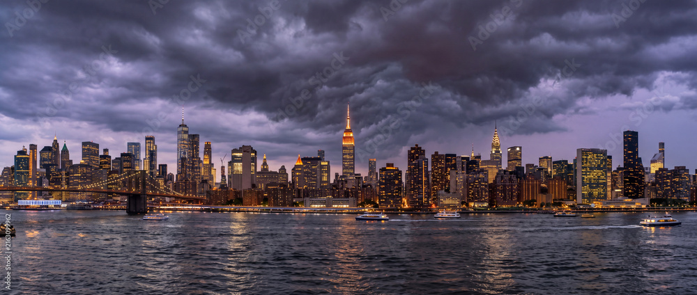 Naklejka premium Dramatic Manhattan Skyline at Dusk Beneath Dark Storm Clouds