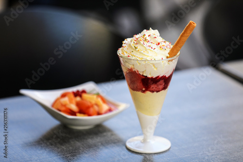Fotografie Layered fruit dessert with whipped cream, sprinkles and wafer
