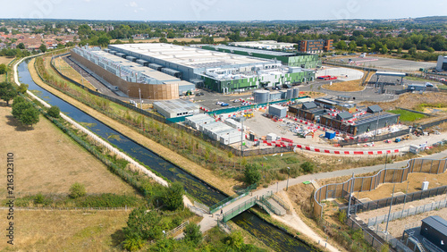 Aerial view of a hyperscale data center complex with air handling units and chillers, adjacent to a canal and green fields in Hereford, England, United Kingdom.