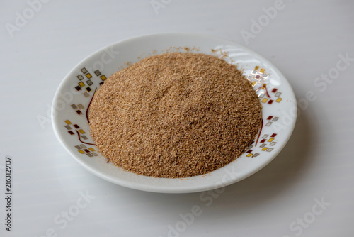 Heap of raw wheat bran flakes in small plate on white background. Natural cereal husk ingredient, dietary fiber nutrition, and organic food concept.
