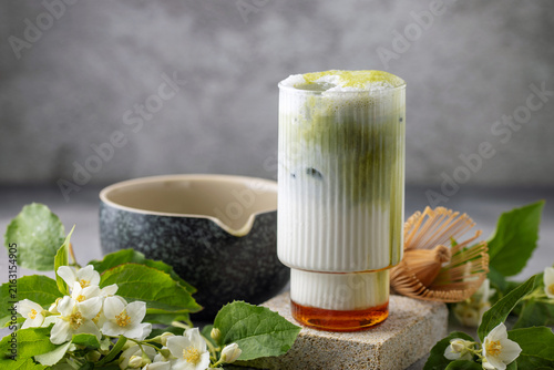 Green jasmine milk with macha tea in glass with jasmine flowers. Trendy drink