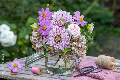 Blumenstrauß mit Dahlien, Herbstanemonen, Rose und Hortensienblüten im Glas im Garten
