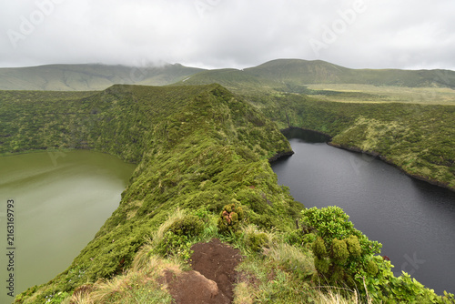 Volcanic craters, Lagoa Negra and Lagoa Comprida next to each other surrounded by green vegetation on Flores Island, rain clouds, Azores