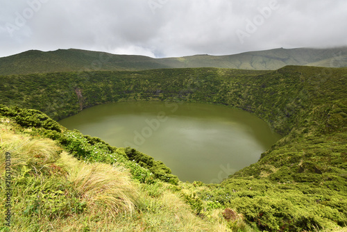 Volcanic crater, Lake Negra surrounded by green vegetation on Flores Island, rain clouds, Azores