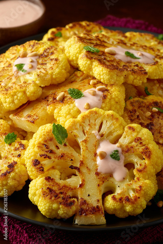 Roasted Cauliflower Steaks with Tahini Sauce and Pine Nuts on a Plate