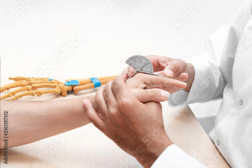 Foto Physiotherapist measuring finger joint range of motion with goniometer during or