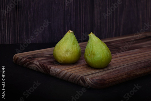 Two green figs on a wooden board