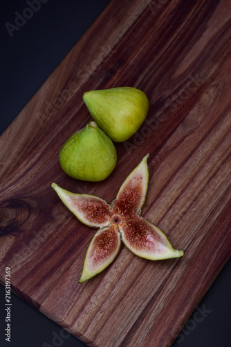 Fresh green figs and a sliced fig served on a wooden charcuterie board