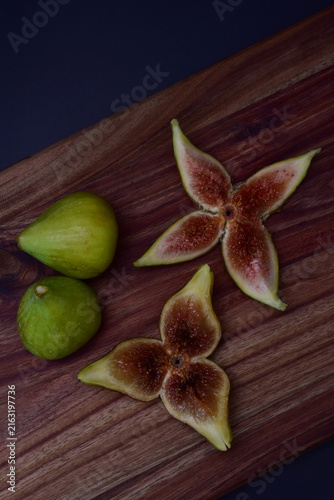 Decorative fresh green figs whole and sliced on a wooden board