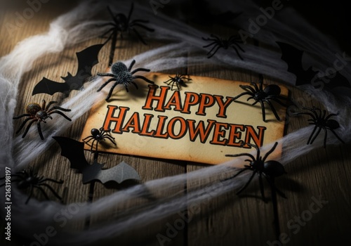 Spooky halloween sign surrounded by dark bats and cobwebs on rustic wooden background