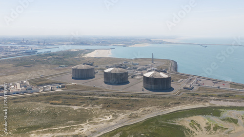Aerial view of Dunkirk LNG Terminal featuring large storage tanks situated on the coast with industrial infrastructure and the sea in Loon-Plage, Hauts-de-France, France.