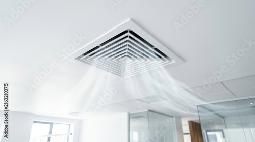 White ceiling ventilation vent in a modern home room.
