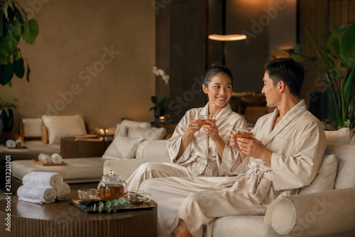 happy asian couple relaxing in luxury spa resort with tea