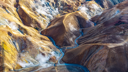 Aerial view of Kerlingarfjoll with colorful geothermal mountains, steam vents, and a winding river in Hrunamannahreppur, Iceland.