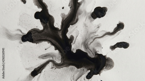 Black ink splatter explosion on white surface for abstract art and creative design projects