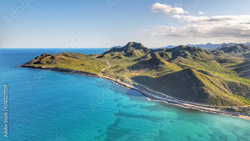 Aerial view of the coastline and mountains of Parque Nacional Cabo Pulmo with turquoise waters and a winding road in Cabo Pulmo, Baja California Sur, Mexico.