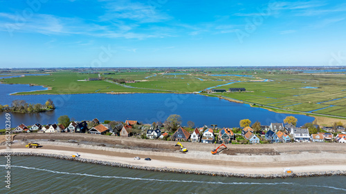 Bild auf Leinwand Dike reinforcement work with village houses along an inland lake in Europe