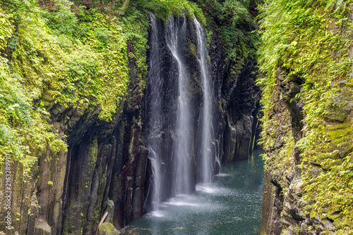 the narrow Takachiho gorge with the Manai waterfalls in the spring, surrounded by fresh green vegetation and no people