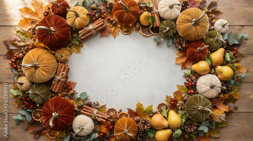 Autumn harvest wreath with pumpkins, pinecones, and berries on rustic wooden background