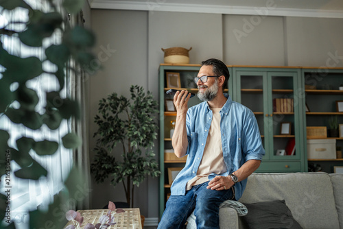 Foto Man recording voice message on phone at home