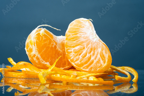 Quadro su tela Fresh peeled mandarin orange segments placed on orange zests with reflection on dark background