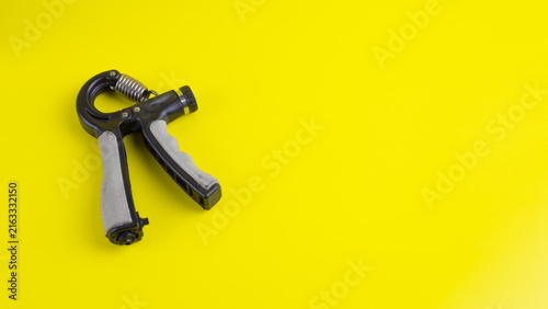 Obraz na płótnie Flat lay adjustable hand gripper on bright yellow background with ample copy space
