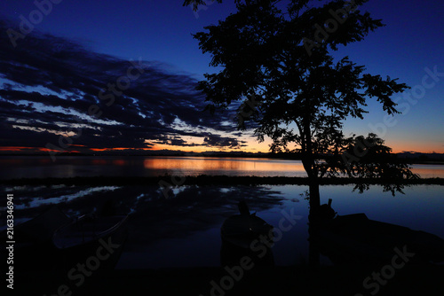 Photography Silhouette of trees and boats at sunset by the lake