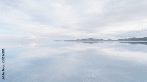 Minimalist Salt Flat Landscape with Perfect Cloud Reflection on Mirror Surface Under a Soft Pastel Blue Sky at Dawn