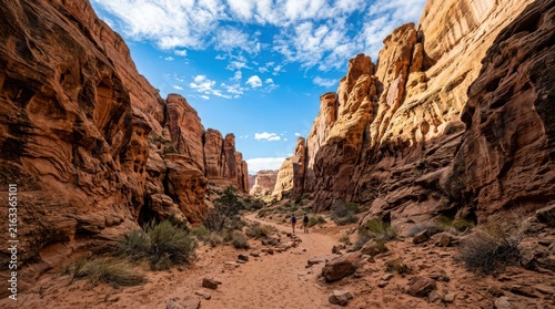 Dramatic sandstone canyon walls framing a dry sandy pathway under bright blue sky sandstone canyons