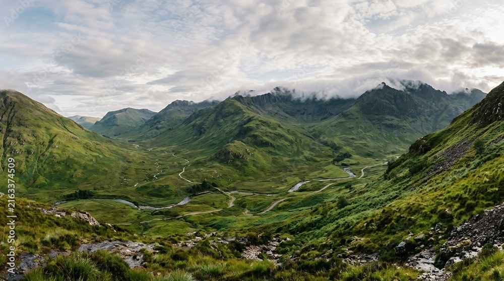 Fototapeta premium Majestic Green Highland Mountains with Winding River Valley and Misty Cloud Covered Peaks at Sunrise Landscape