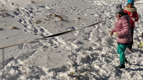 Two little girls play snowballs on the snowy mountain slopes.