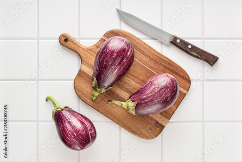 Three fresh purple eggplants  on wooden cutting board