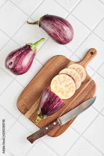 Three fresh purple eggplants  on wooden cutting board