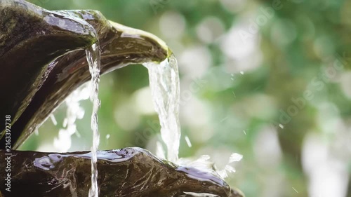 Close Up Water Flowing in Decorative Garden Stone Fountain with Soft Bokeh Background