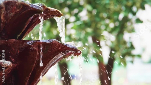 Water flowing down decorative ceramic fountain in park or garden slow motion close up