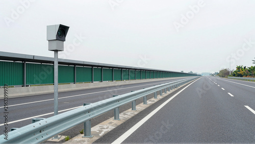 Roadside traffic surveillance camera monitoring an empty modern highway under overcast skies