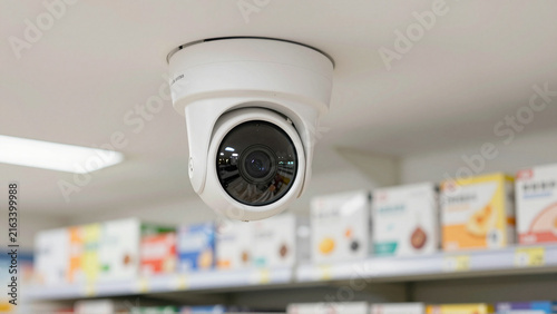 Ceiling mounted surveillance camera monitoring merchandise shelves inside a modern retail store