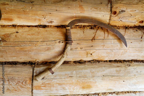Konstfotografi An antique metal sickle on the wall in a wooden hut