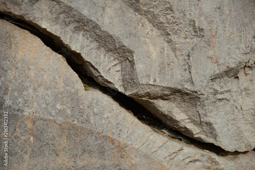 Bild auf Leinwand Deep natural fissure in weathered limestone, revealing a rugged surface with gra