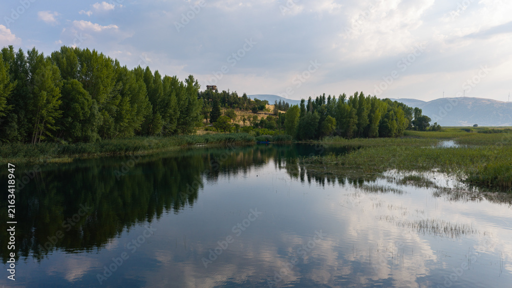Obraz premium A soothing natural landscape where the trees and the sky are reflected on the calm surface of the lake.