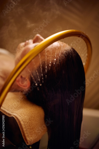 фотографія Close up of woman enjoying soothing hair rinse at wellness spa.
