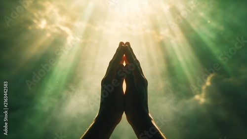 Silhouette of Hands Raised in Prayer with Glowing Celestial Sunbeams and Heavenly Light Rays in Spiritual Green Sky