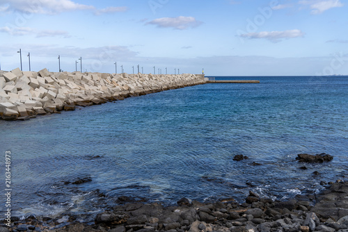 A stunning coastal scene on Lanzarote featuring a concrete breakwater and beautiful turquoise waters on a sunny day.