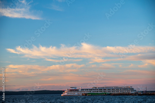 Petrozavodsk, Karelia, Russia, 15 August 2026 River cruise ship docked at pier on Lake Onega at sunset, pink clouds, blue sky, forested shoreline in distance