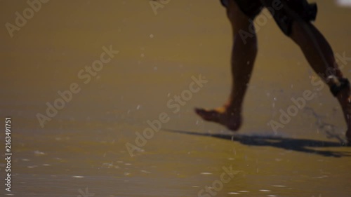 close up of surfers feet as they run on the sand