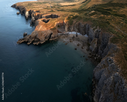 Fotografía Drone view of rugged sea cliffs and rocky coastline at Flimston Bay, Wales, with calm blue water and remote coastal scenery
