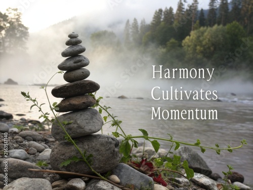 Balanced stones stacked in a tranquil river setting with misty forest background.