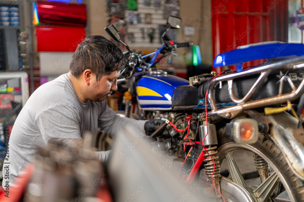 Fototapeta premium Mechanic repairing motorcycle in a workshop