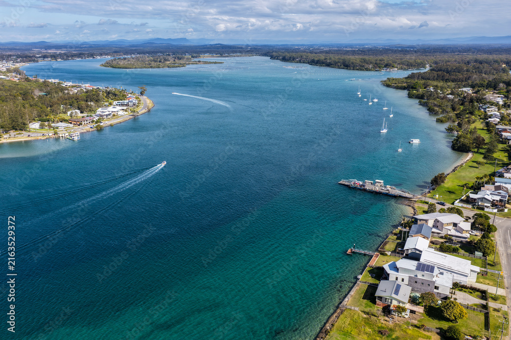 Fototapeta premium Aerial view of the Settlement Point Ferry crossing the Hastings River in Port Macquarie, connecting Settlement Point with the northern side of the river amid the scenic waterways and coast