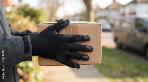Cardboard box delivery same day with gloved hand near residential street showing secure parcel handling and convenient home service